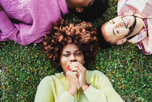 Afro woman lying down on grass with friends at park photo
