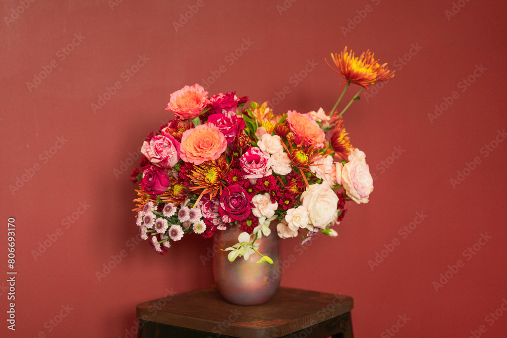 bouquet of flowers in vase behinds red background