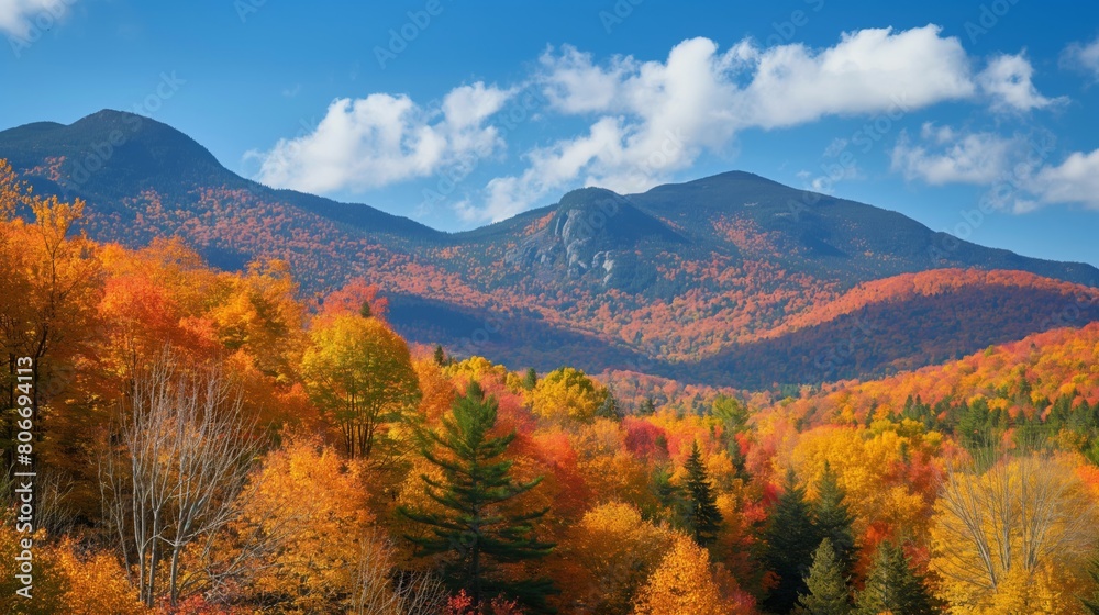 Vibrant autumn colors engulf a majestic mountain range under a clear blue sky