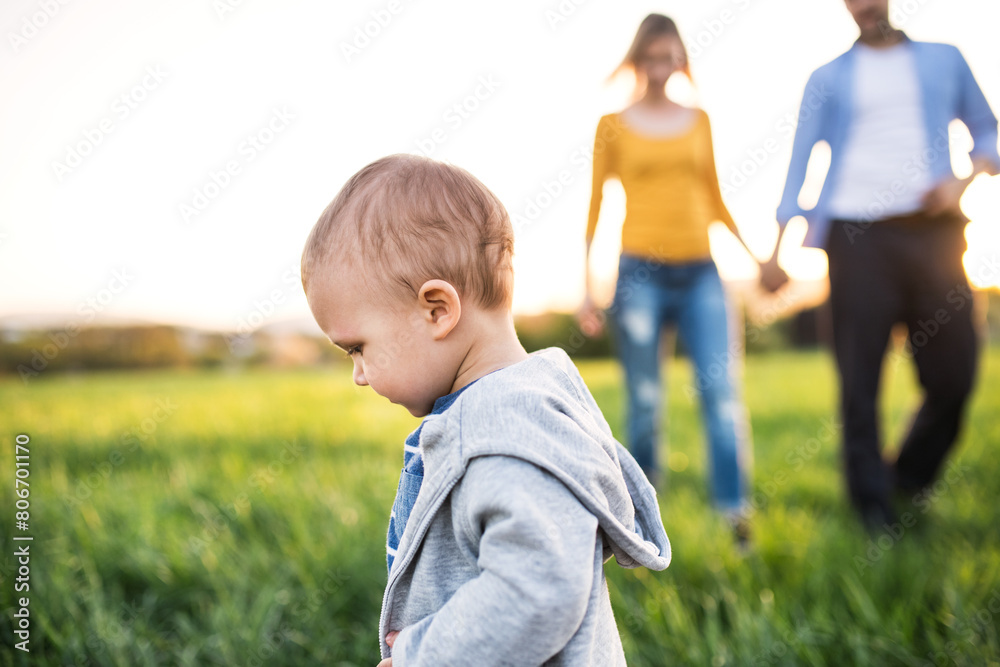 Cute toddler running in front of parents during, family walk k in spring nature. Happy family moment for new parents Cute toddler running in front of parents during, family walk k in spring nature. Happy family moment for new parents