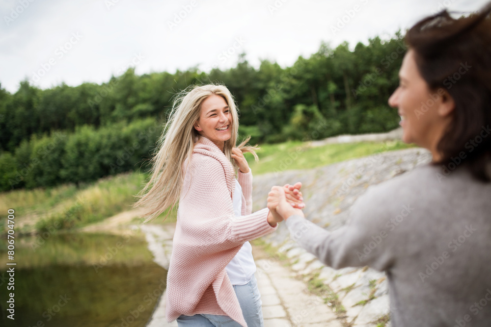 Adult daughter spending time with her mother. Mom and daughter outdoors, on walk by reservoir, lake embankment. Unconditional, deep maternal love, Mother's Day concept..