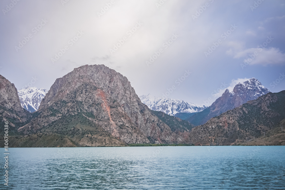 Panoramic view of blue Iskanderkul lake and rocky mountains in Tajikistan on a cloudy cloudy day