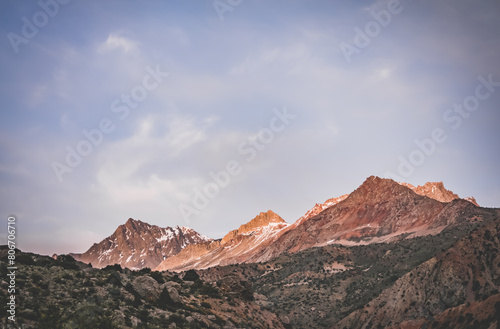 Rocky peaks of mountains and ridges illuminated by the bright orange sunset sun