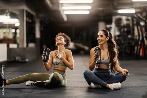 Panel kuchenny z motywem Two happy sporty friends sitting on a gym floor and drinking water while taking a break.