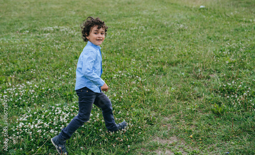 Playful young boy with curly hair running joyfully across a blooming meadow, embodying the freedom and excitement of childhood