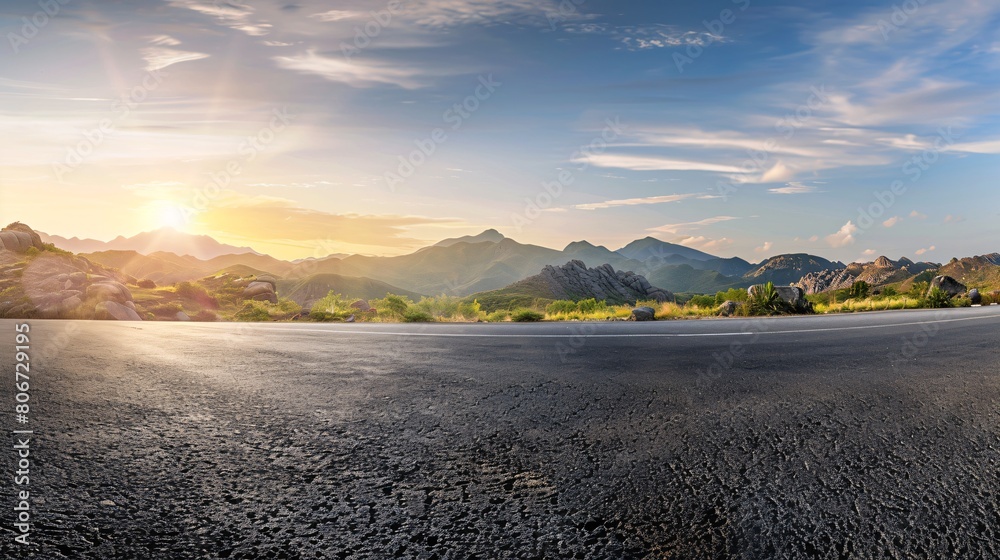 Fototapeta premium Sunrise over a mountain landscape and a paved road, offering a wide vista.