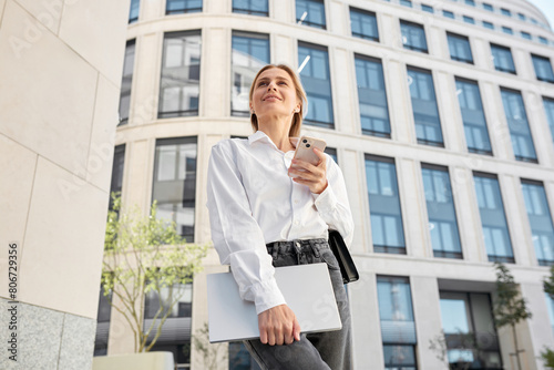 Portrait of a young blond woman dressed in a white shirt before an interview against the background of an office building