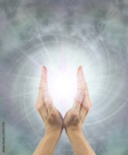 Silver Starlight Healing Energy Intention - Beautiful silver grey vortexing energy field with a pair of female hands around a bright starlight orb ideal for a healing theme  
