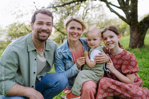 Family portrait with daughter and small toddler, baby, outdoors in spring nature. © Halfpoint
