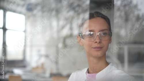 Smiling scientist with safety goggles lloking through window photo