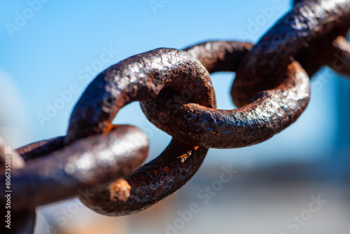 Rusty and heavily weathered old chain with massive chain links. Close-up of a forged anchor chain with selective sharpness and corroded surface. Silhouette with blurred background. photo