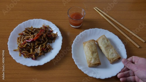 Chinese spring rolls with red sweet and sour sauce, Chinese chopsticks. Asian Chinese cuisine. background with brown table.