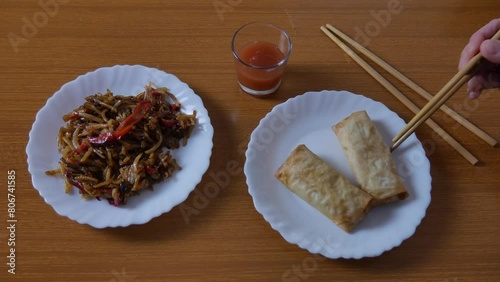 Chinese spring rolls with red sweet and sour sauce, Chinese chopsticks. Asian Chinese cuisine. background with brown table.