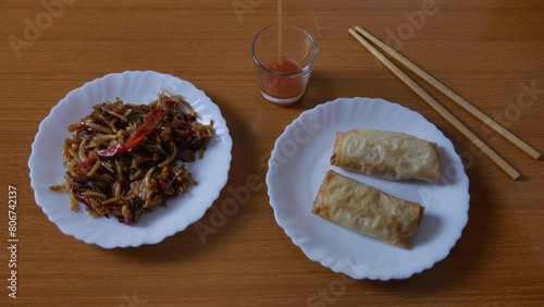 Chinese spring rolls with red sweet and sour sauce, Chinese chopsticks. Asian Chinese cuisine. background with brown table.