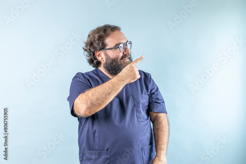 Horizontal banner of smiling young male doctor showing and presenting something with hand, isolated on blue background with copy space on right