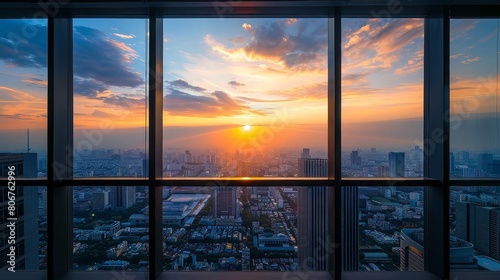 sunset cityscape view from high - rise apartment window featuring towering buildings and a clear blue sky  with a prominent glass window in the foreground