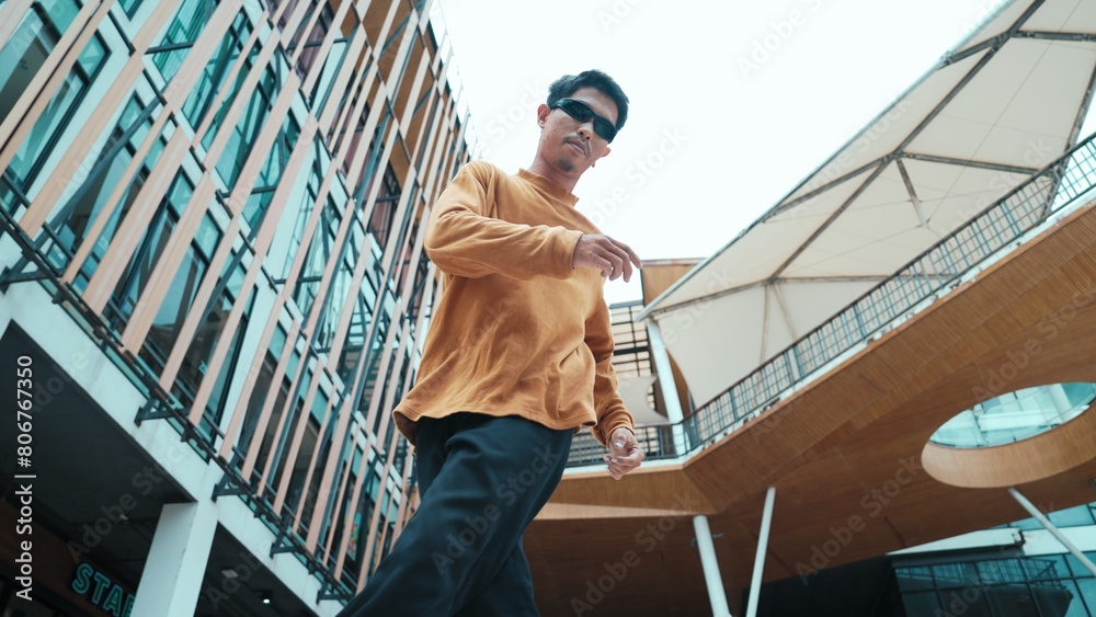 Hispanic dancer looking at camera while dancing in hip hop style. Young attractive hipster moving and dancing to music. Motion shot of break dancer perform b-boy dance Outdoor sport 2024. Endeavor.