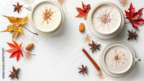  Two cups of coffee with cinnamon and star anise on a pristine white surface Autumn leaves surrounding, along with extra cinnamon sticks