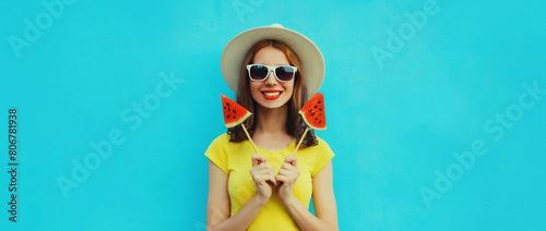 Summer portrait of happy young woman with lollipop watermelon wearing straw hat on blue background
