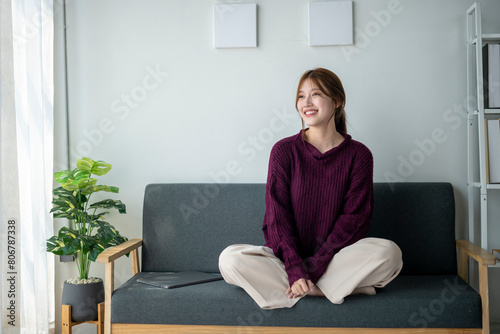Foto A woman is sitting on a couch with a laptop on her lap