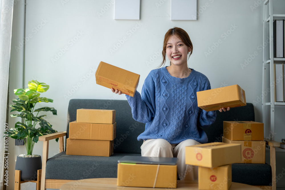 A woman is sitting on a couch holding a stack of boxes. She is smiling and she is happy A woman is sitting on a couch holding a stack of boxes. She is smiling and she is happy