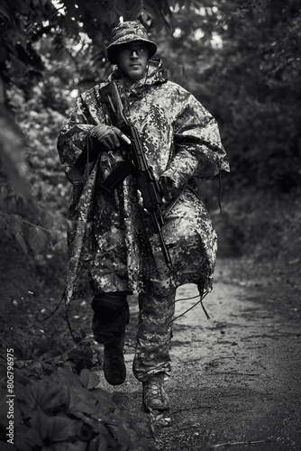 A Ukrainian soldier in military uniform with a machine gun in his hands walks through the forest
