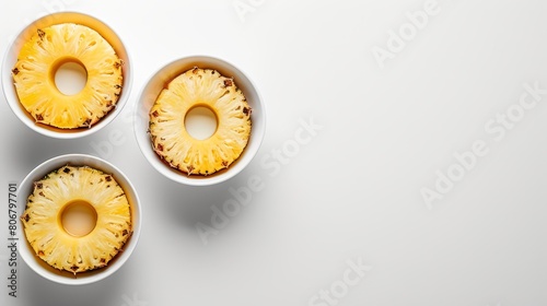   Three bowls hold sliced pineapples atop a white table One additional bowl, likewise filled, sits beside them