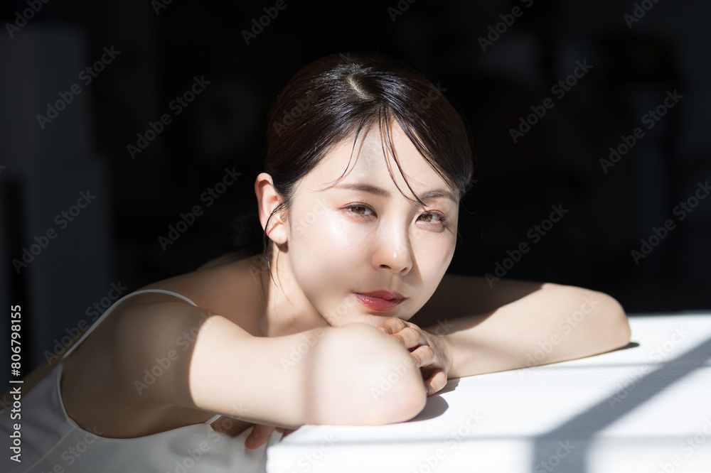 Obraz premium 透明感や艶のある色っぽい美容やビューティーの若い女性のうつ伏せクローズアップのアンニュイな表情 背景がグレーのカメラ目線