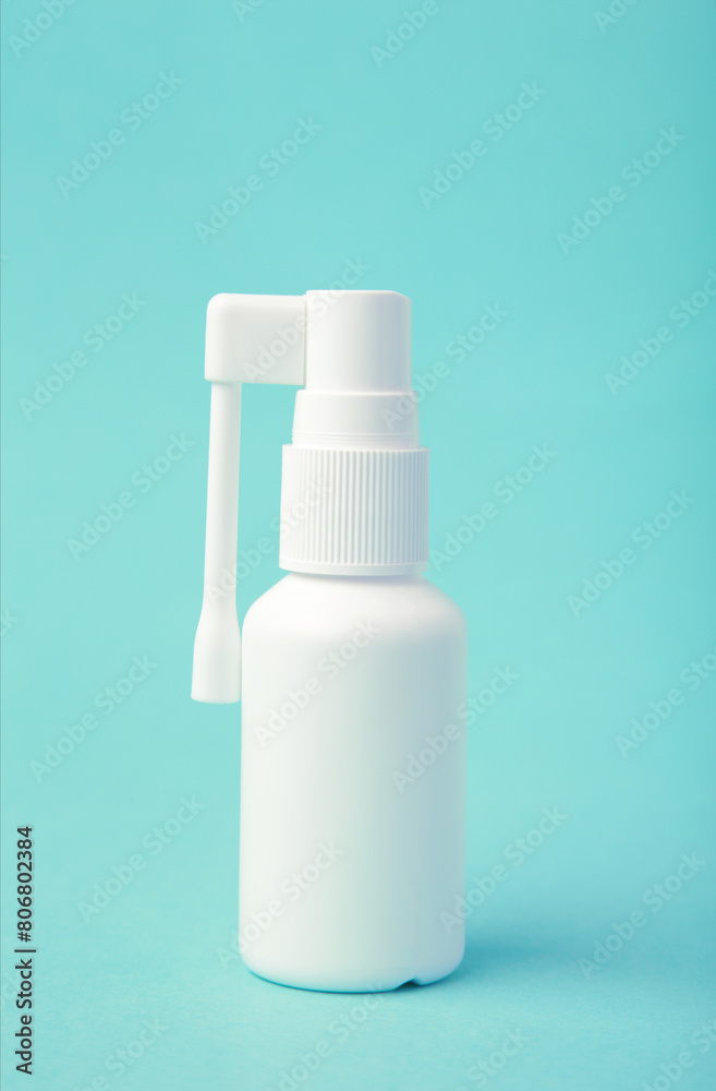 Throat spray medication in a white bottle on light blue background.