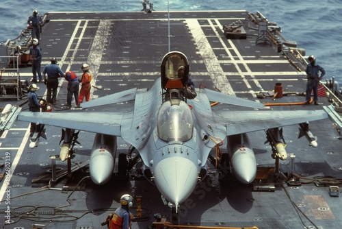 F-16 undergoing maintenance on a carrier deck, crew members working, tools and equipment scattered around