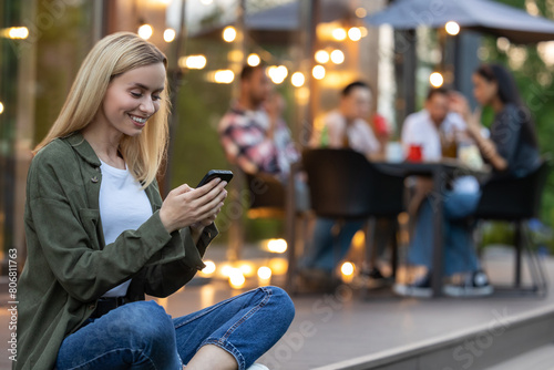 Pretty young woman using mobile phone during picnic in backyard at home