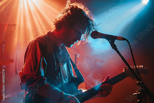 Focus on the guitarist bathed in a spotlight, showcasing their passion and skill, with the microphone stand adding a touch of authenticity to the performance setting. photo