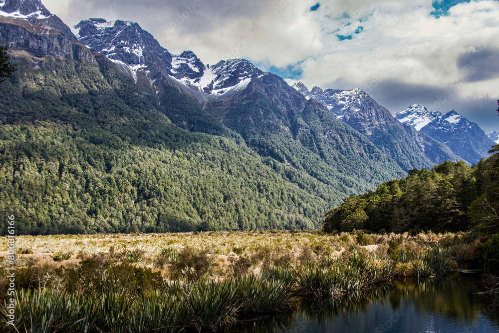 By the shore of Mirror Lakes on Milford Sound Highway Fiordland New Zealand looking up at the snow capped mountains