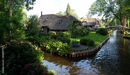Typical houses of Giethoorn, Netherlands with gardens. Town is know as "Venice of the North". Landscaped view of the famous village with canals and rustic thatched roofs in the farm area.