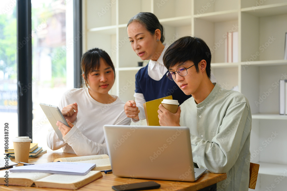 Mature female lecturer helping student during class. Education concept Mature female lecturer helping student during class. Education concept