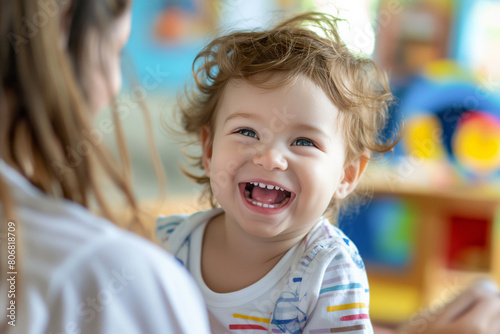 Happy young child with a joyful laugh in colorful daycare, mother nearby.
