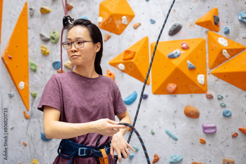 A young Asian woman on a climbing wall. A Korean girl climbs a bouldering wall