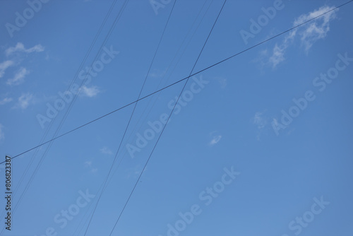 Electrical wires between buildings against a background of blue sky with clouds