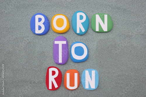 Born to run, creative slogan composed with hand painted multi colored stone letters over green sand
