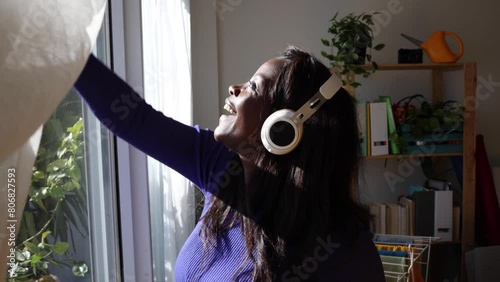 African American woman cleaning windows while singing with her headphones