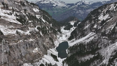 A magnificent aerial view captures the enchanting beauty of snow, lake, and mountains at Tahlalpsee, Filzbach, Glarus Nord, Switzerland. photo