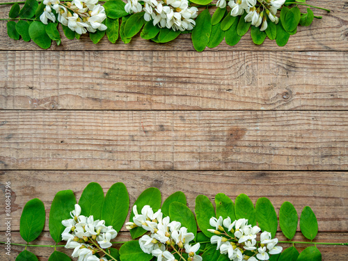 frame made of acacia flowers and leaves on wooden background with copy space