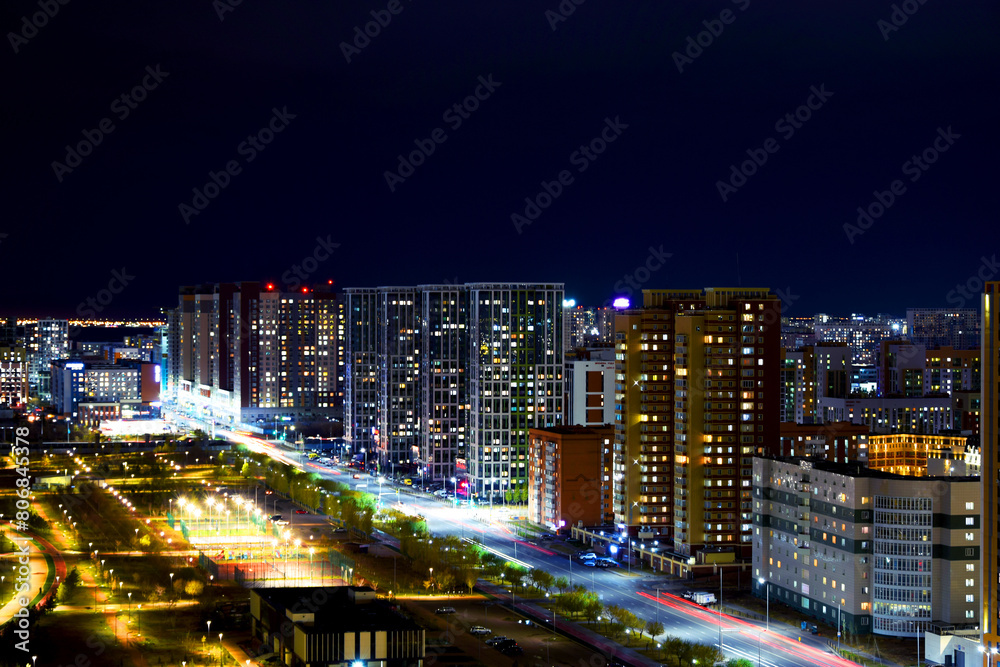 Obraz premium The center of the night city of Astana, illuminated by the light of houses, lanterns and car headlights. Kazakhstan, Asia. High-rise buildings.