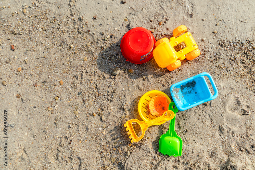 Set of plastic beach toys on sand on a sunny day. Top view. Set of plastic beach toys on sand on a sunny day. Top view.
