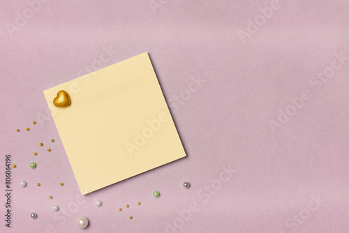 Yellow paper note sticker with decor on a pink background. Space for text. Flat lay, top view.