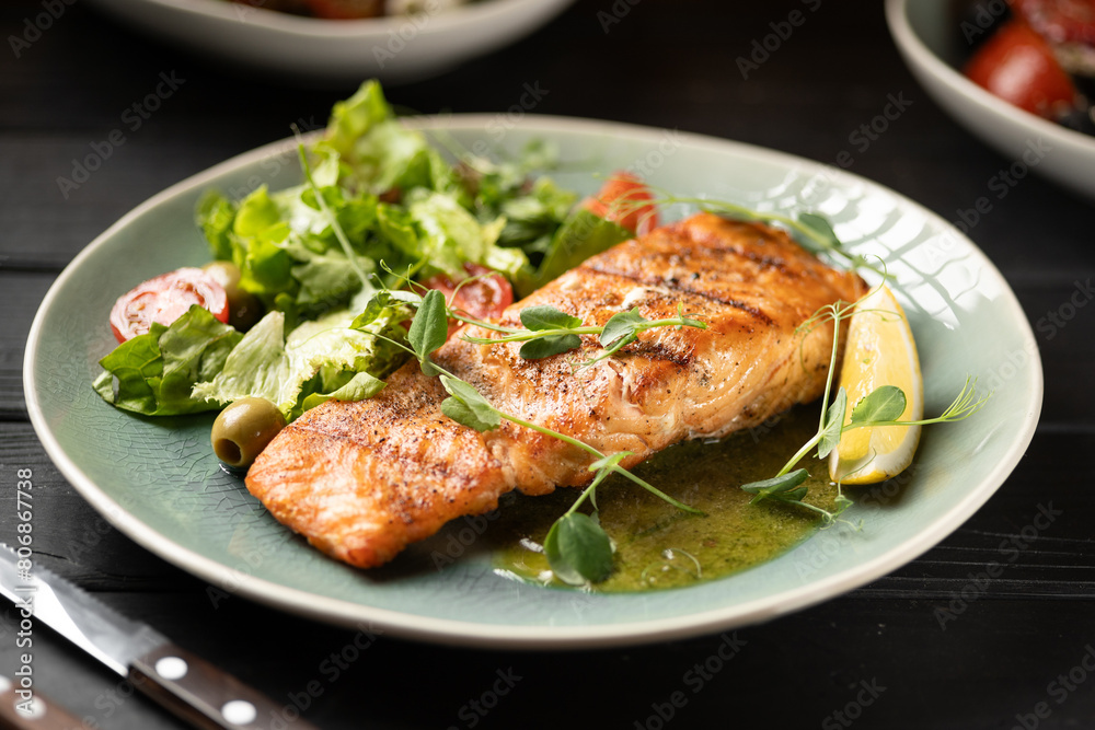 Grilled salmon fillet served with greens and vegetables in a restaurant. Seafood and diet concept.