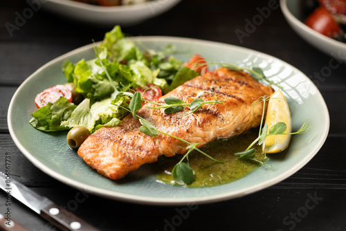 Grilled salmon fillet served with greens and vegetables in a restaurant. Seafood and diet concept.