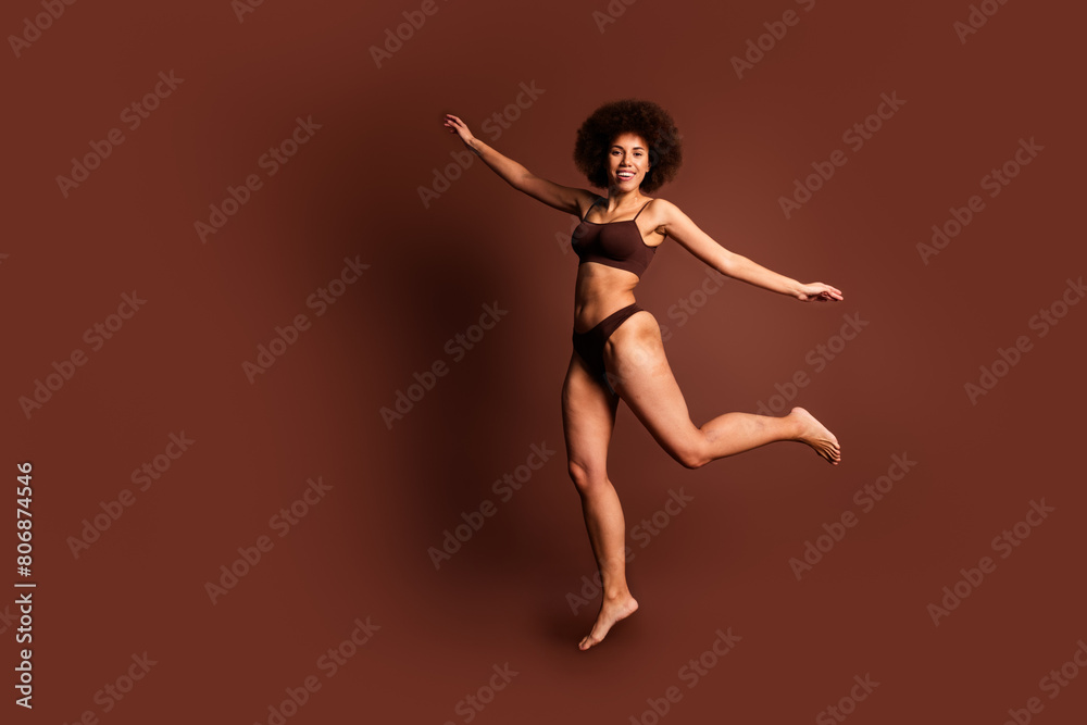 Full length photo of carefree sweet lady underwear jumping enjoying women rights empty space isolated brown color background Full length photo of carefree sweet lady underwear jumping enjoying women rights empty space isolated brown color background