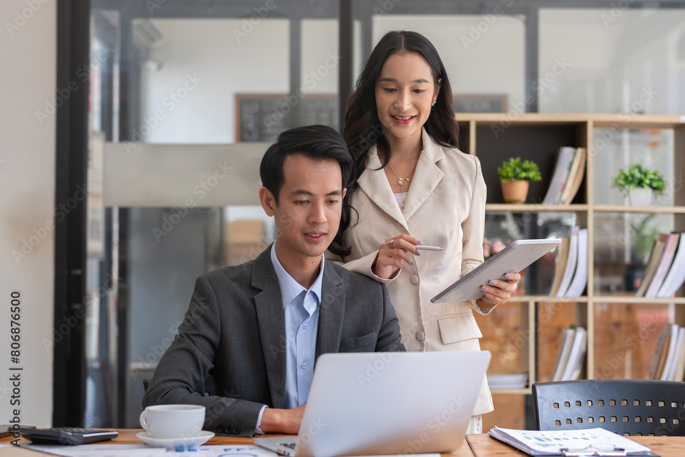 Fototapeta premium A young businessman and a female Asian accountant are discussing financial accounting and business planning together in the office.