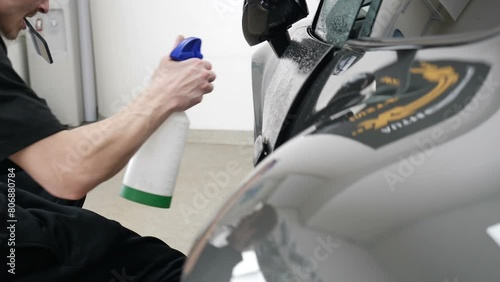 Close up of paint protection film installation on front bumper of modern luxury car. PPF is polyurethane film applied to car surface to protect the paint from stone chips, bug splatter, and abrasion.